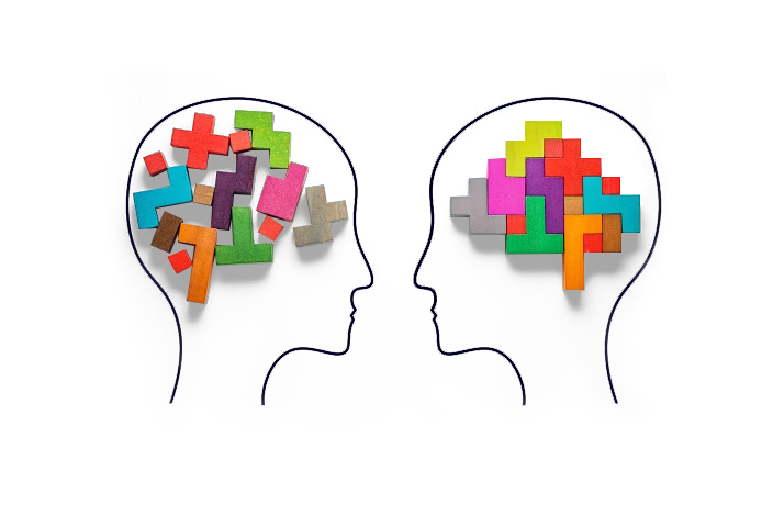 Two silhouetted heads facing each other, each containing a collection of colorful puzzle pieces representing different aspects of cognition and mental processes.